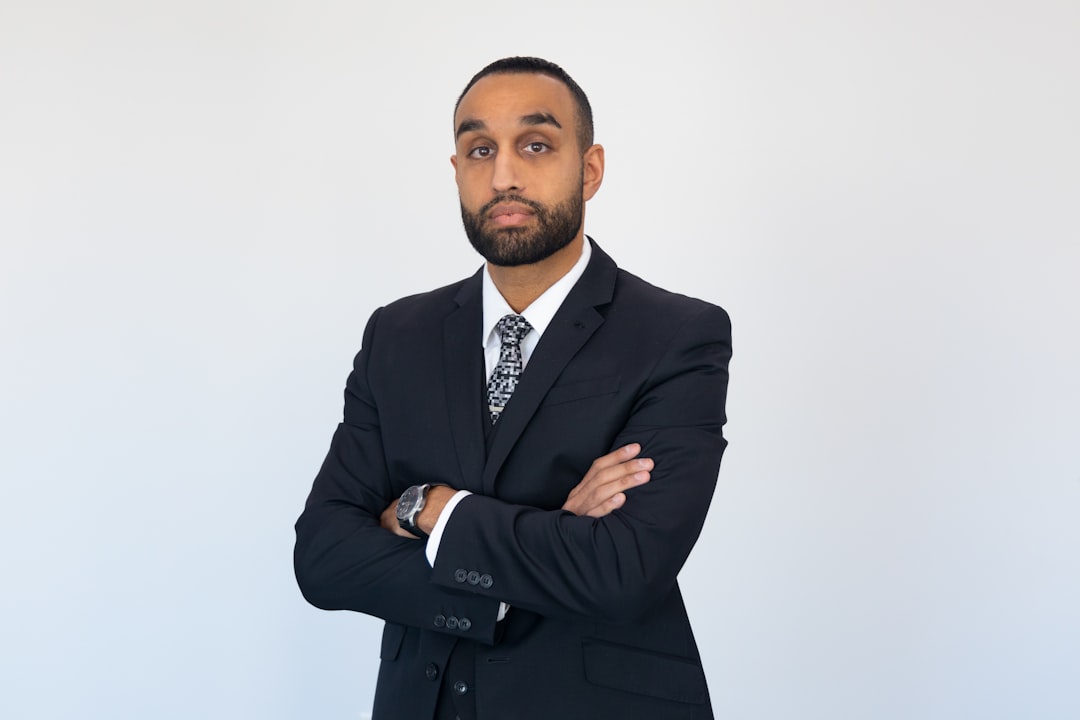 Tall male lawyer standing confidently in expensive suit with arm crossed
